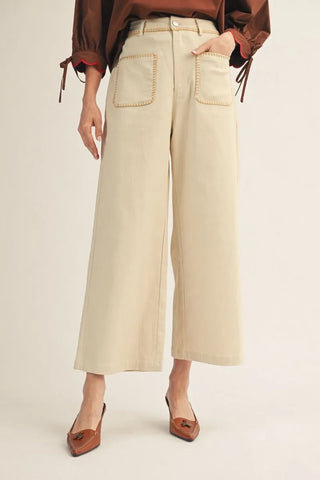 Person wearing beige wide-leg pants with a plain background