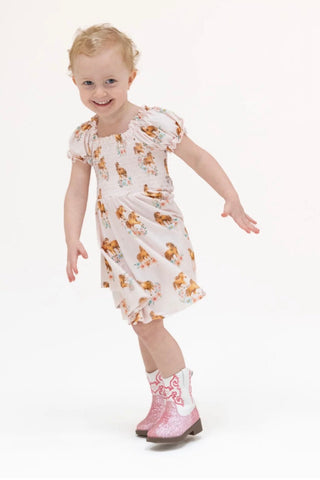 Little girl in pink dress with ponies on it.