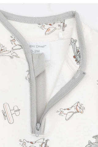 Close-up of a baby garment with a light gray zipper and collar trim, featuring a white fabric body printed with a retro airplane pattern in gray and muted orange. A brand label reading 'Bel Deair' is visible inside the neckline.