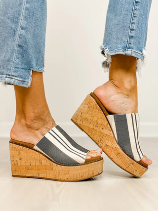 Wedges with striped design and cork sole worn with rolled-up jeans on a neutral background