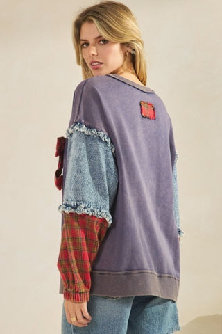 Woman wearing a purple sweater with denim and plaid sleeves on a beige background