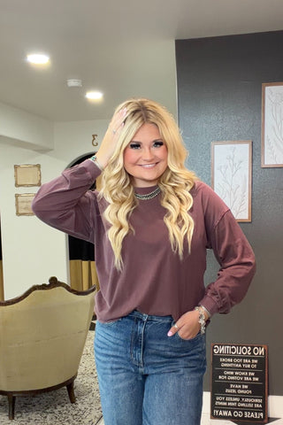 Woman in a purple shirt and blue jeans posing indoors.