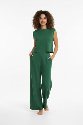 Woman wearing a light gray sleeveless top and wide-leg pants on a white background