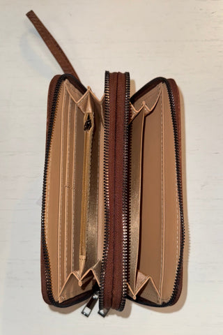 Open brown wallet with a strap on a light beige background