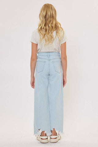 Person wearing light blue jeans and a white t-shirt on a plain background