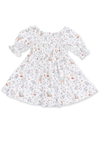 A white long-sleeve baby dress with a smocked bodice and an all-over whimsical print of deer, rabbits, and small flowers in muted pastel colors, shown flat against a white background.