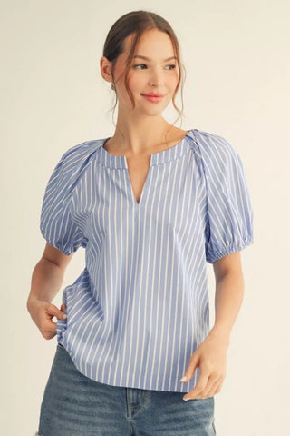 Woman wearing a blue and white striped shirt against a beige background