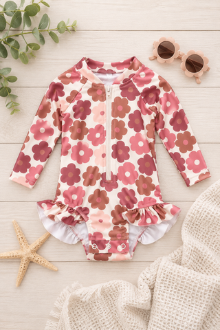 Floral patterned baby outfit with ruffles on a light wooden surface.