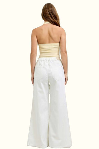 Woman wearing a strapless top and white wide-leg pants on a white background