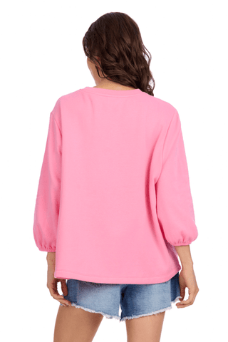 Person wearing a pink long-sleeve top and denim shorts on a white background