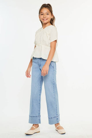 Young girl wearing a white top and light blue jeans on a white background
