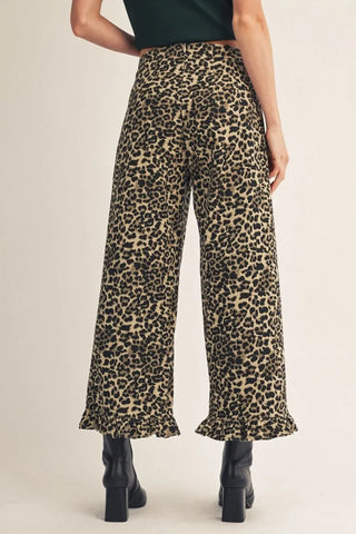 Leopard print pants worn by a person on a beige background