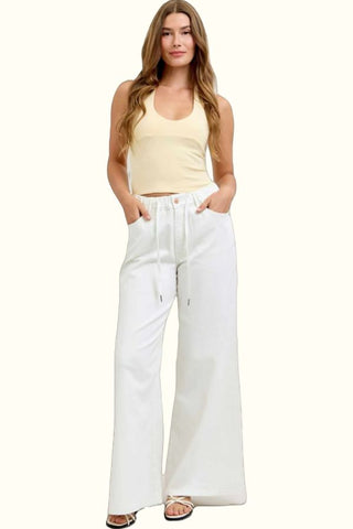 Woman wearing a yellow top and white wide-leg pants on a white background