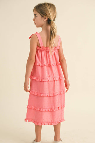 Young girl wearing a pink dress with ruffled layers on a beige background