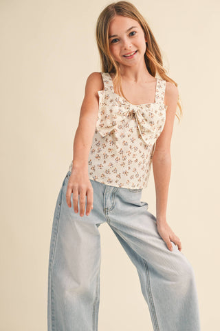 Young girl wearing a floral top and light blue jeans on a beige background