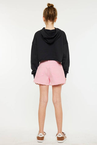 Person wearing a black hoodie and pink shorts on a white background