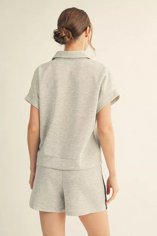 Person wearing a gray sleeveless top and shorts set on a beige background