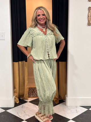 Woman wearing a light green dress standing in a room with a checkered floor.