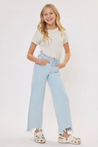Young girl wearing a white t-shirt and light blue jeans on a plain background
