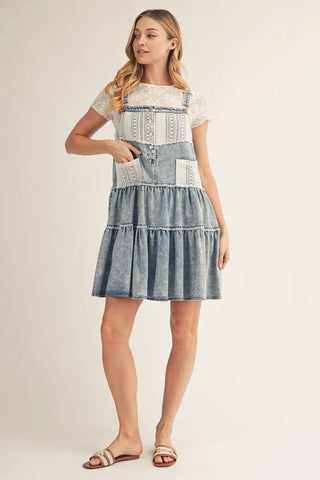Woman wearing a denim dress with lace details on a white background