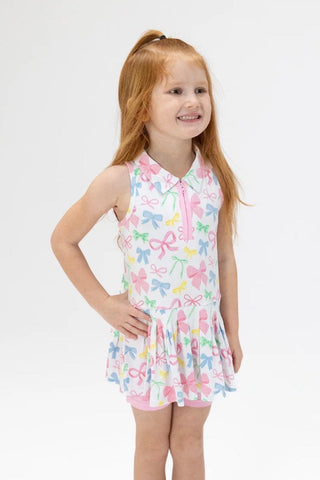 Young girl wearing a colorful dress with bow pattern on a white background