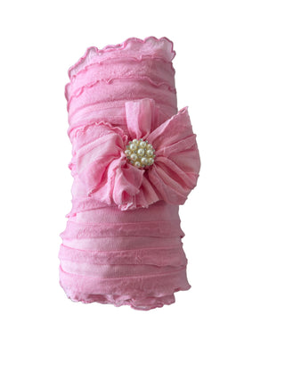 Pink headband with a flower and pearl center on a marble surface