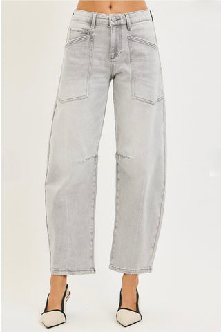 A model is shown from the waist down wearing light gray cropped jeans with a relaxed, wide-leg fit and decorative patch pockets, paired with black and white slingback heels against a plain white background.