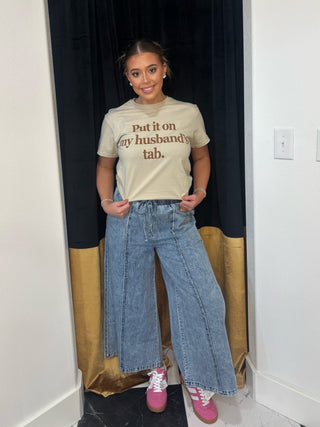 Person wearing a graphic t-shirt and jeans standing in a doorway.