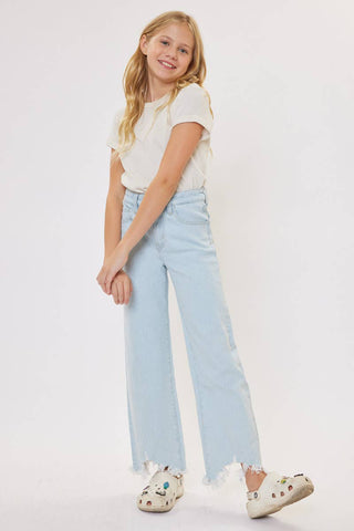 Young girl wearing a white t-shirt and light blue jeans on a plain background