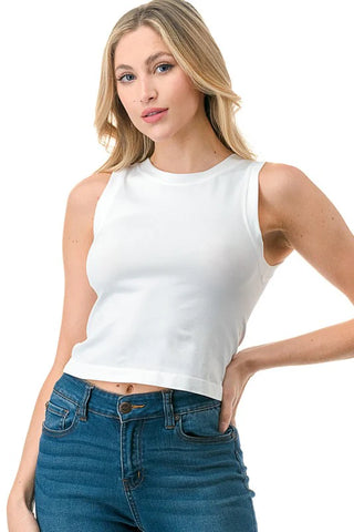 Woman wearing a white sleeveless top and blue jeans on a white background