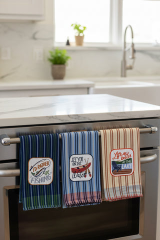 Three striped towels with lake-themed designs on a marble surface