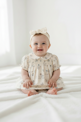 Infant girl wearing cream dress with matching bloomers