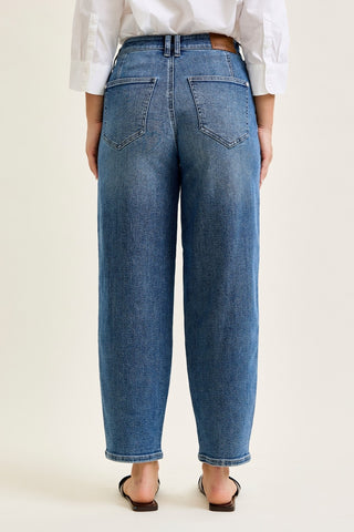 Person wearing blue jeans and a white shirt on a plain background