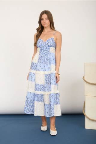 Woman wearing a blue and white floral patchwork dress against a plain background