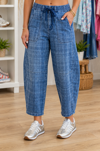 Woman wearing plaid print denim jeans and silver sneakers in a boutique.