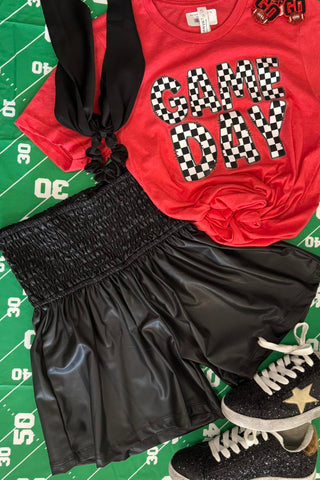 Red 'Game Day' shirt with black shorts and sneakers on a sports-themed background