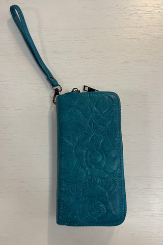 Blue embossed wallet with wrist strap on a light wooden surface