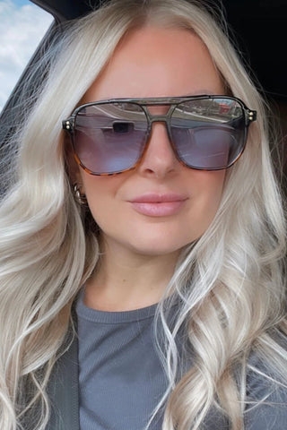 Woman wearing large sunglasses with a blurred outdoor background