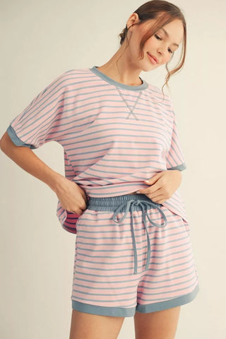 Woman wearing a pink and blue striped pajama set on a beige background