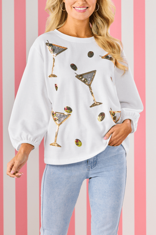 Woman wearing a white sweatshirt with martini glass designs on a striped background