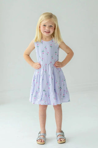Young girl wearing a light purple dress with floral pattern on a white background