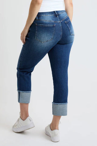 Person wearing blue jeans with rolled-up cuffs on a white background