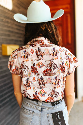 Person wearing a patterned shirt with horse designs and a white cowboy hat.