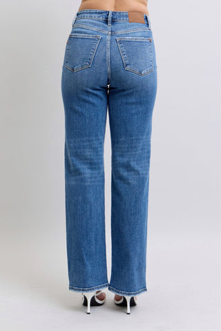 Blue jeans worn by a person on a plain background