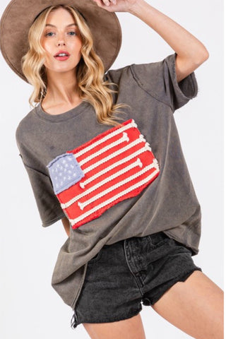 Woman wearing a gray oversized t-shirt with an American flag design on a white background