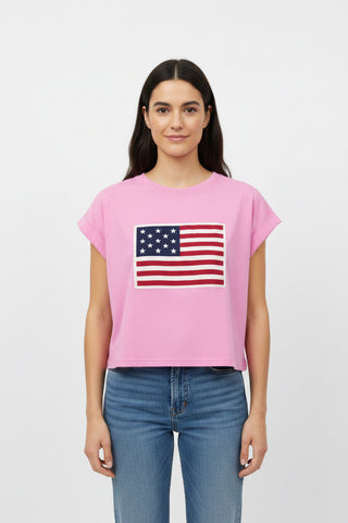 Woman wearing a pink t-shirt with an American flag design on a plain background