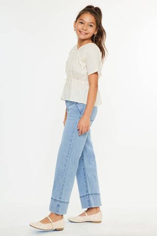 Young girl wearing a white blouse and light blue jeans on a white background