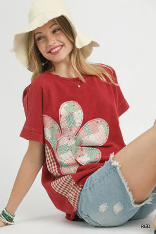 Woman wearing a red t-shirt with a floral design and denim shorts on a white background