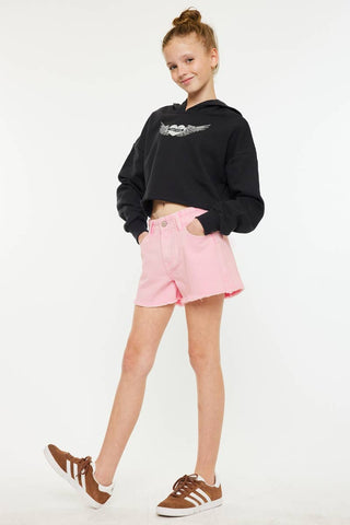 Person wearing a black hoodie with a logo and pink shorts on a white background