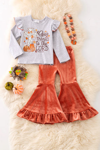 Children's outfit with gray long-sleeve top and orange velvet pants on a fluffy white surface.